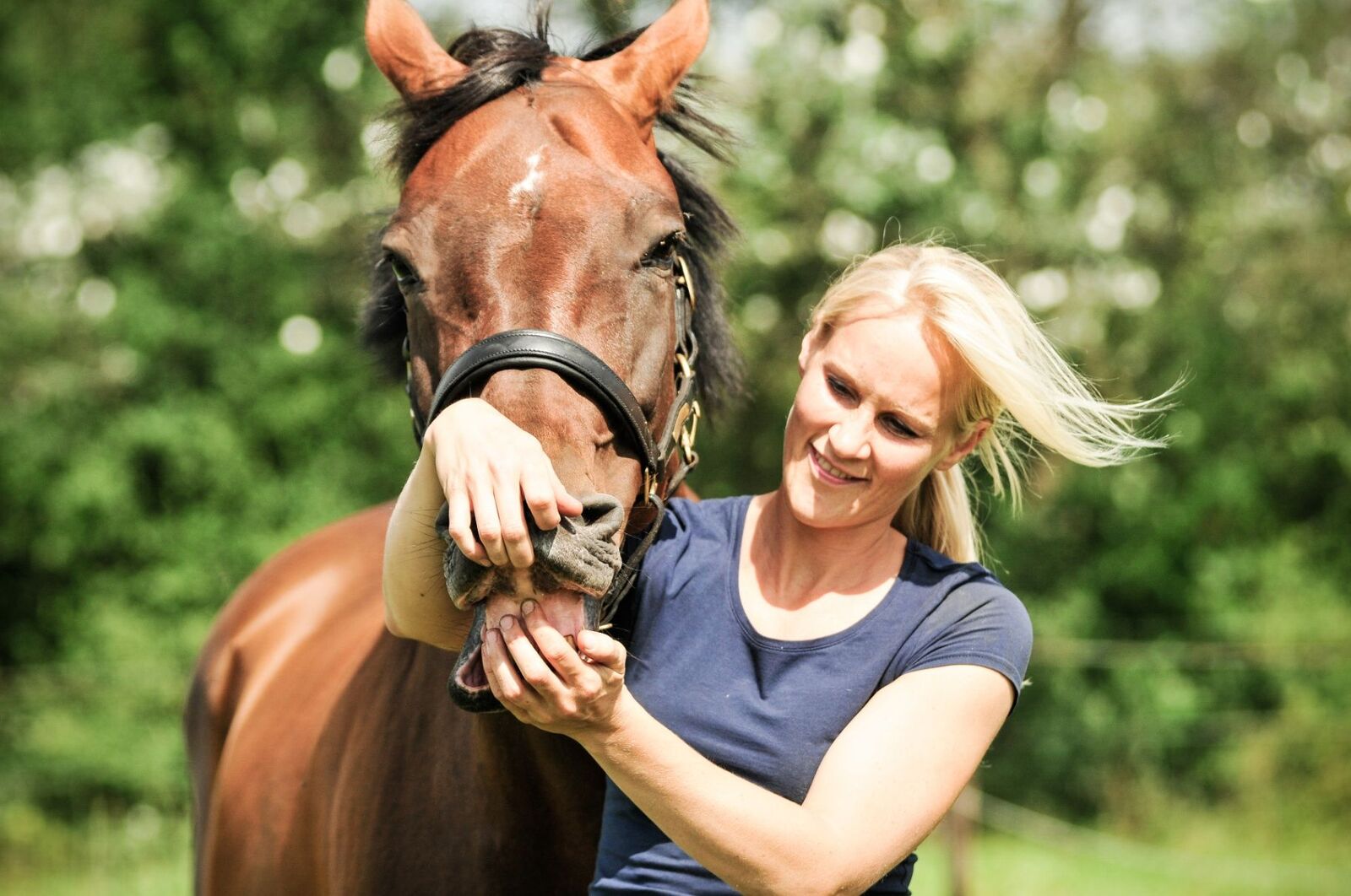 Evy lacht naar de camera terwijl ze een bruin paard vasthoudt